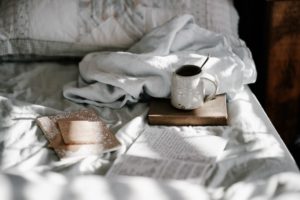taza de cafe y libros sobre un colchon