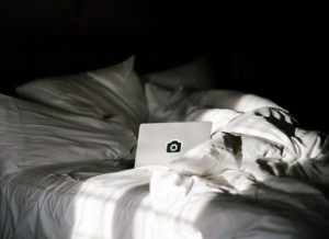 portatil en una cama sabanas blancas