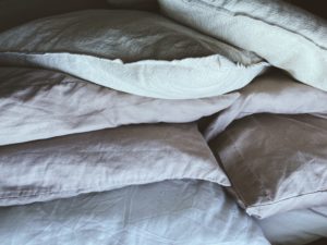 cama con almohadas y sabanas enrolladas