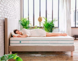 Mujer descansa sobre cama con colchón blanco