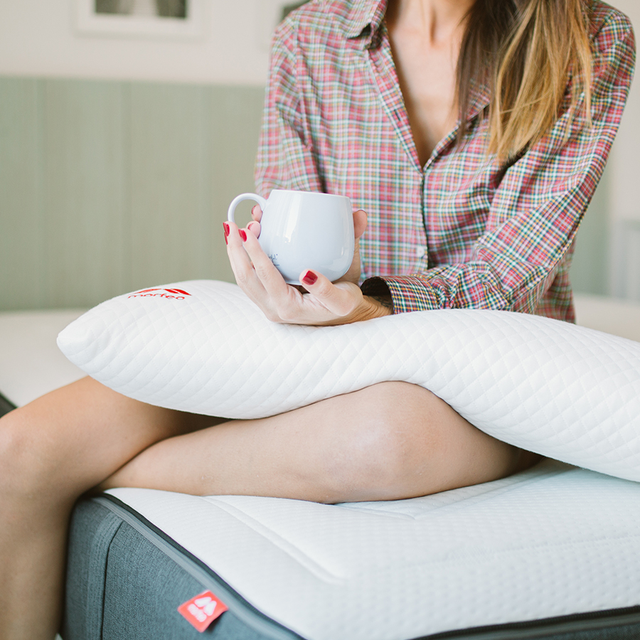 una chica con un cafe en su colchon con una almohada