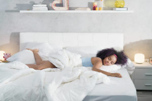 Mujer descansando boca abajo con un pie sobre la almohada