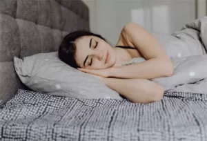 una muchacha descansando sobre un colchon y almohada