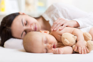 mujer con un niño y su peluche durmiendo sobre un topper