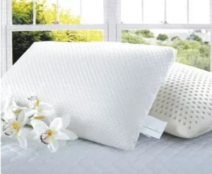 dos almohadas de latex blancas con dos flores sobre la cama