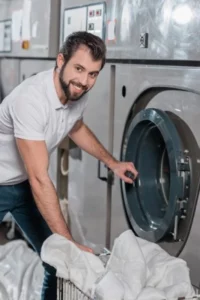 hombre sacando edredon de la secadora