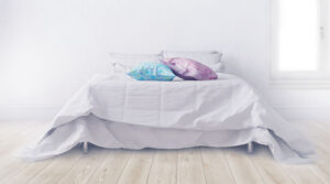 edredon blanco con almohadas azul y rosada