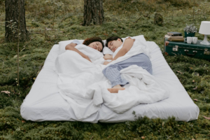 pareja durmiendo sobre colchon en la grama