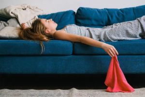 muchacha tumbada sobre el sofa verde con un pañuelo rojo en la mano