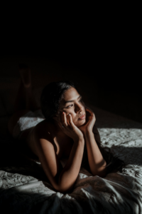 mujer apoyada sobre las manos en la cama mirando al frente a oscuras