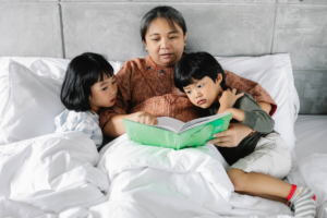 abuela con sus nietos en la cama leyendo un libro