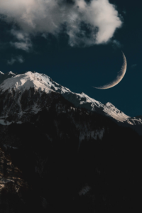 montaña oscura con luna creciente y nubes