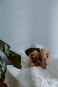 mujer durmiendo de lado y una planta en el cuarto