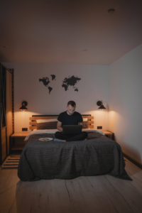 hombre trabajando en laptop sentado en la cama a oscuras