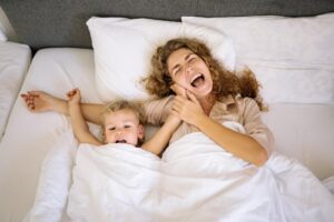 madre e hija sonriendo acostadas en la cama