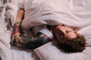 hombre con el brazo tatuado durmiendo boca arriba