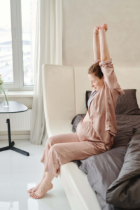 mujer sentada en la cama estirandose embarazada