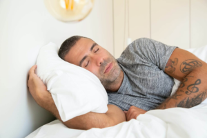 hombre durmiendo abrazando una almohada blanca