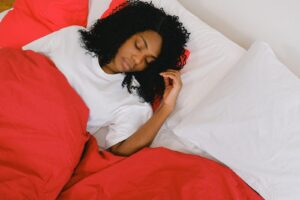 mujer durmiendo arropada con sabana rojas 