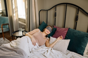mujer en juego de cuarto con antifaz gris y almohadas verdes